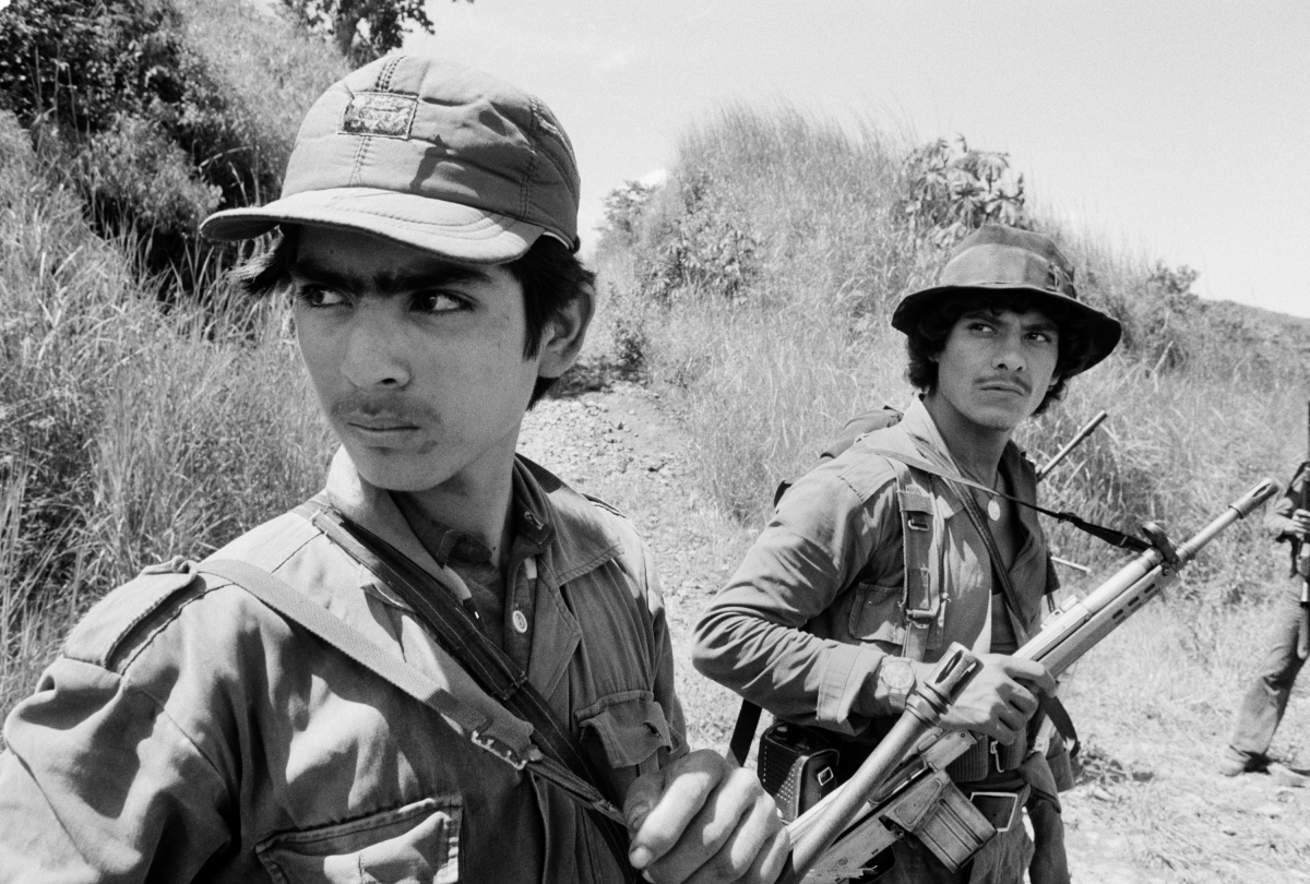 Two guerrillas from the Farabundo Martí Popular Liberation Forces (FPL) watch a low-flying Salvadoran military observation plane near the Guazapa volcano on the road to Suchitoto, El Salvador, on Oct. 21, 1983.