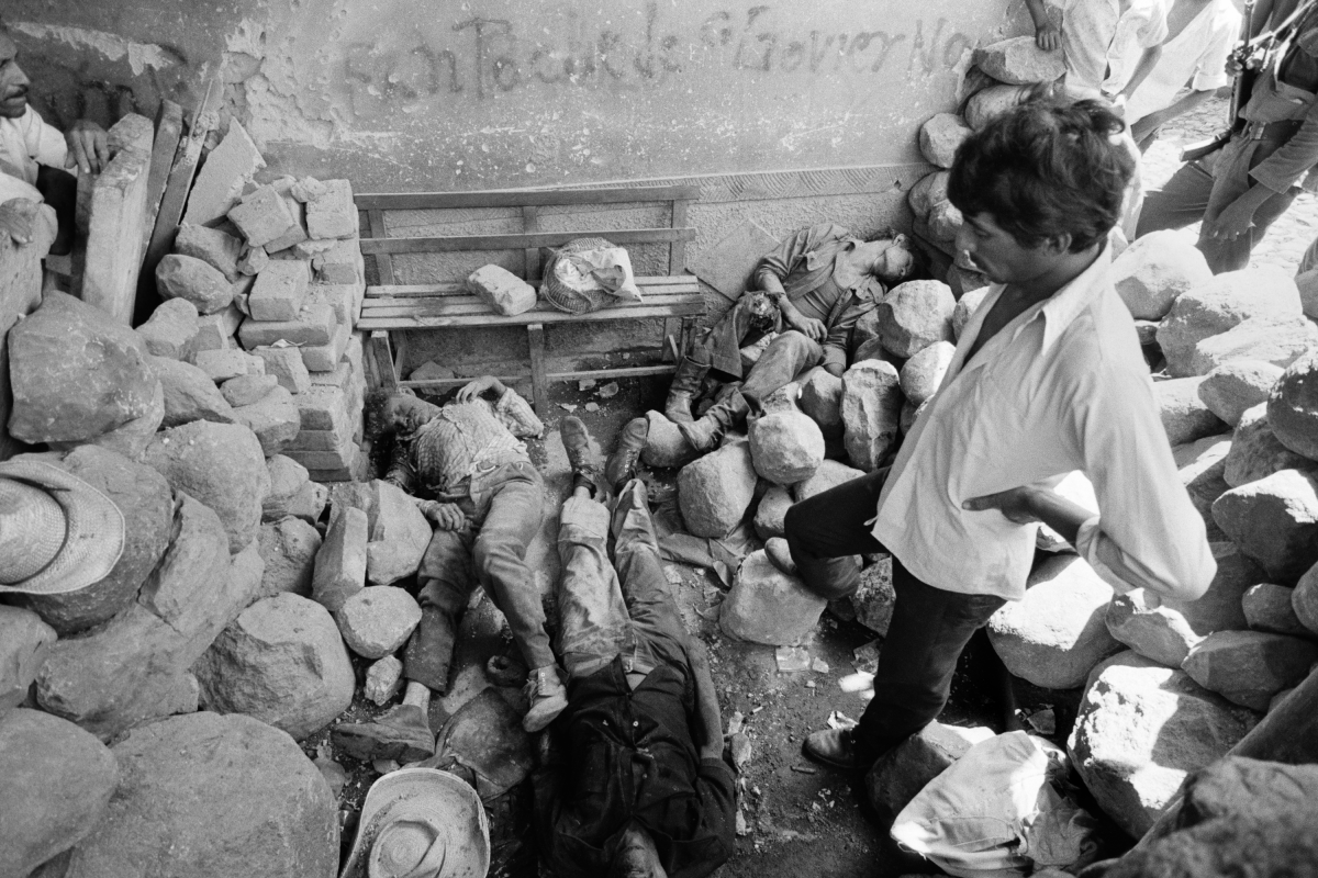 Civilians look over the dead bodies of three civil defensemen killed during an overnight attack by guerrillas from the Farabundo Martí National Liberation Front (FMLN) in Santa Clara, El Salvador, in July 1982.