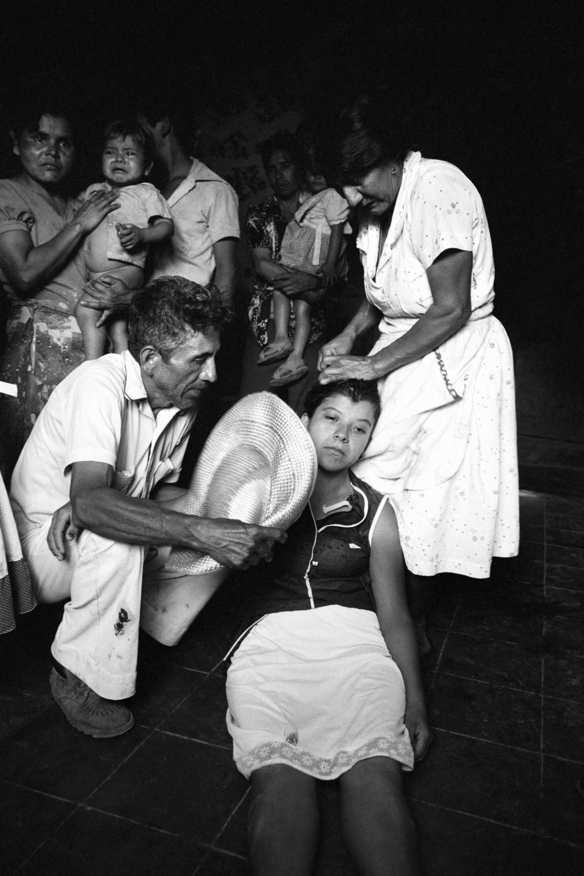 The sister of a civil defenseman (center) faints upon hearing of the death of her brother during an overnight attack on the civil defense post in Santa Clara, El Salvador, in July 1982.