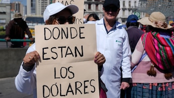 Una trabajadora de una farmacia privada con un cartel en el que reclama por la escasez de dólares en una protesta en el centro de La Paz, Bolivia, el miércoles 22 de mayo de 2024 (AP Foto/Juan Karita)