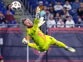 Jonathan Sirois leaps into the air looking at a soccer ball flying past his head