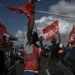 PHILIPPE LOPEZ/AFP Men in gilets wave flags of the French union CGT Martinique during aa go slow operation on the ring road leading to the airport in Fort-de-France, in the French Caribbean island of Martinique.