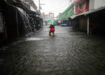 A woman walks along a flooded street during the passage of tropical storm Sara in La Ceiba, Honduras, on November 15, 2024. Honduras' President Xiomara Castro said emergency services had been activated to deal with 'damage already caused by the rains,' warning that Sara's impacts 'could become a catastrophic event.' (Photo by AFP)