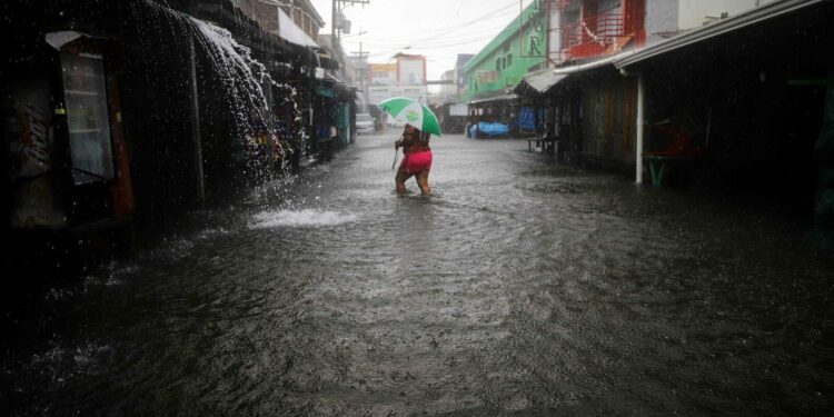 A woman walks along a flooded street during the passage of tropical storm Sara in La Ceiba, Honduras, on November 15, 2024. Honduras' President Xiomara Castro said emergency services had been activated to deal with 'damage already caused by the rains,' warning that Sara's impacts 'could become a catastrophic event.' (Photo by AFP)