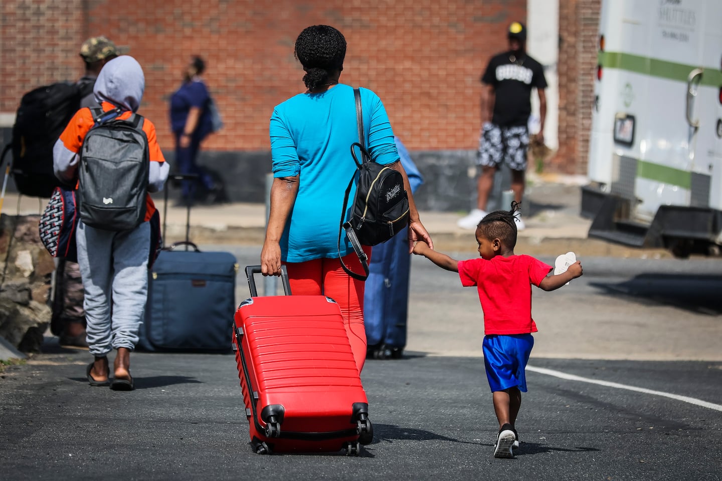 Haitian migrants pulled suitcases behind them as they left the Church of the Holy Spirit in Mattapan in June, where they had spent the day. The migrants would take three trains to Boston Logan Airport, where they'd spend the night and pack up again the next morning. 