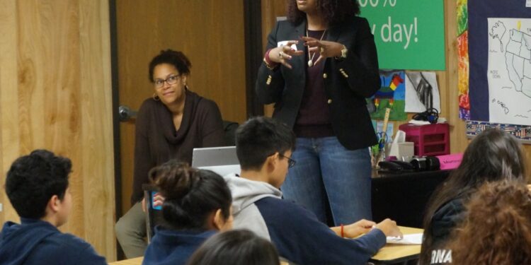 A woman speaks to a classroom of students.