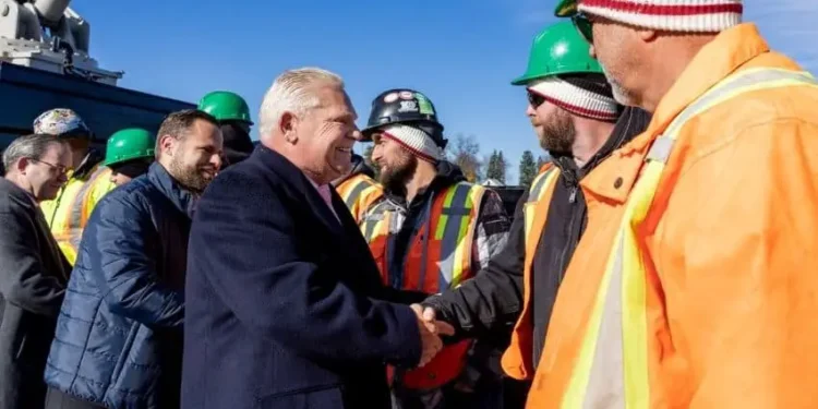 Ontario premier Doug Ford shaking the hand of a worker in an orange hazard and hardhat at a Canadian training facility site for crane operators.