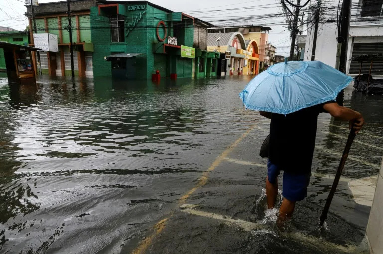 Un hombre camina en una calle inundada durante el paso de la tormenta tropical Sara en La Ceiba, Honduras, el 15 de noviembre de 2024 (ESAU OCAMPO)