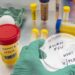 A gloved hand holds a petri dish marked &quot;Avian flu&quot; on a table with other lab equipment