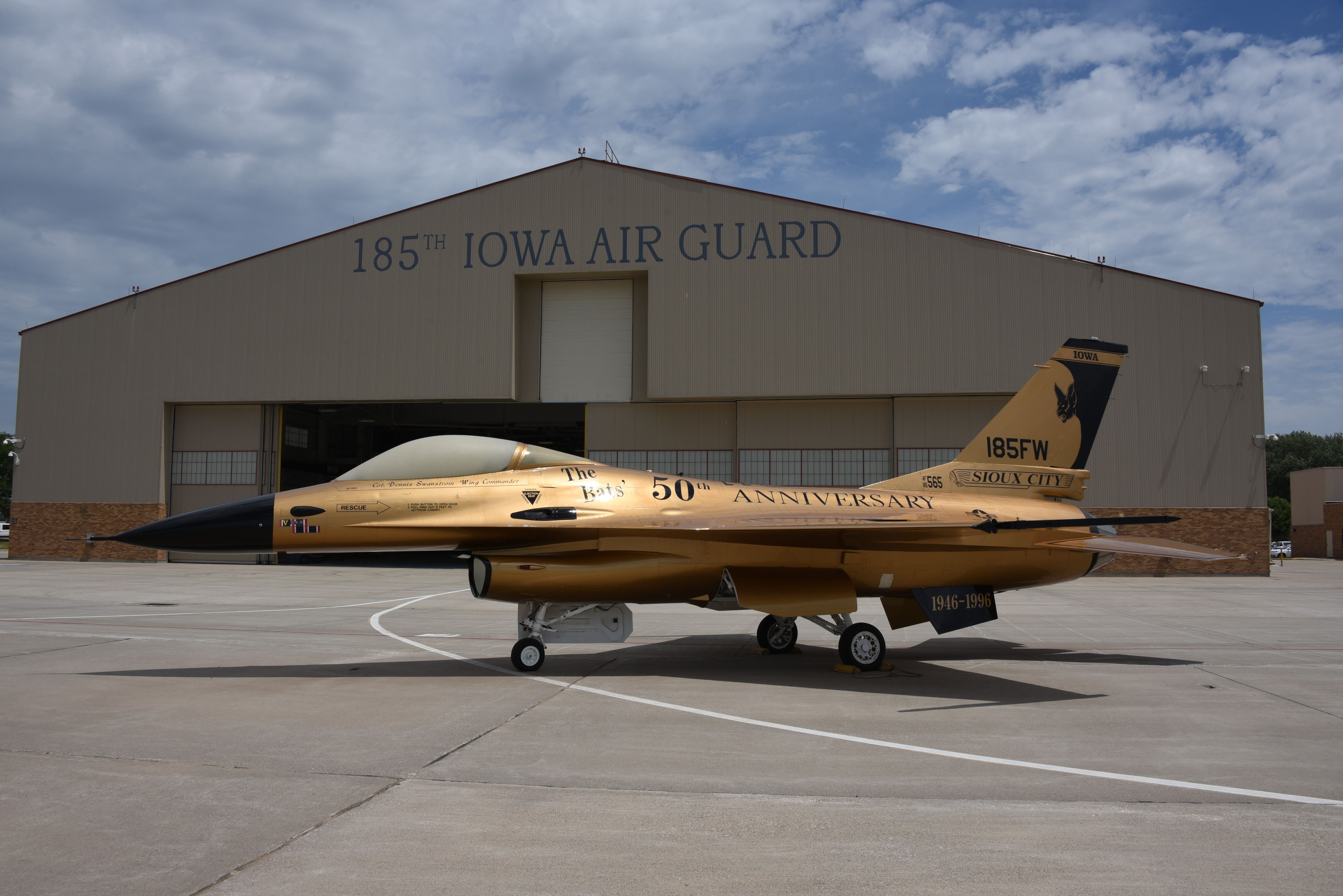 An Iowa Air National Guard General Dynamics F-16C Fighting Falcon in 50th anniversary gold livery on an airport apron.