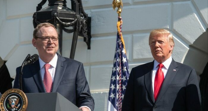 Kevin Hassett speaks at a podium while Donald Trump stands next to him
