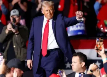 Getty Images Donald Trump walks through an arena crowd with his right fist raised out. Several mobile phones are photographing and videoing him.