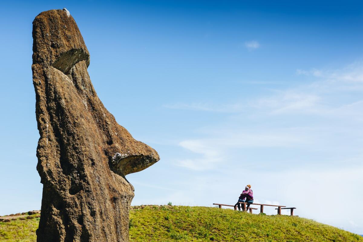 Happy couple in love and Moai statues in the Rano Raraku Volcano in Easter Island, Rapa Nui National Park, Chile