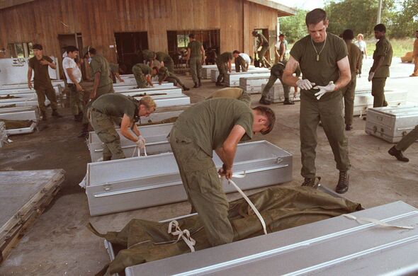 military personnel place bodies in coffins