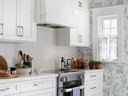 Removing an original window changed the orientation of the kitchen for the better. Sweet toile-style wallpaper and black and white tile floor are period touches.   