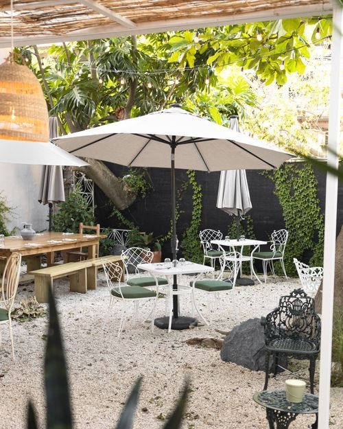 Outdoor seating area with tables and umbrellas in a garden setting