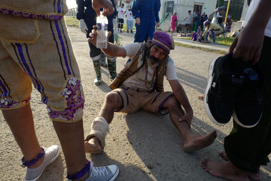 A pilgrim accepts water from medics as he crawls backwards to honor St. Lazarus.