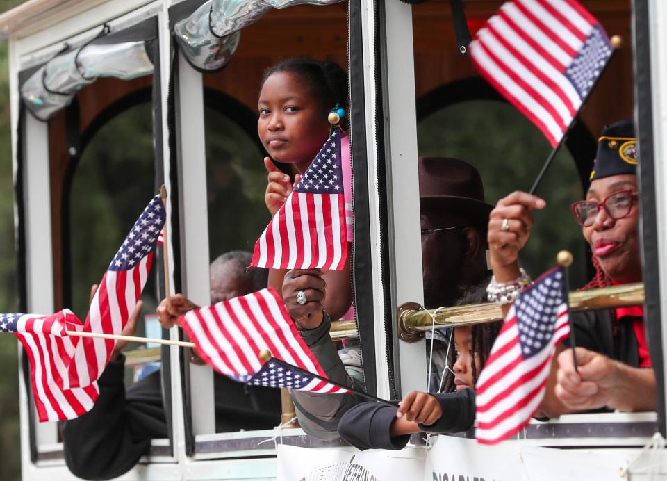 Participants wave flags from the window of the Disabled American Veterans trolley during the annual Savannah Veteran's Day Parade in Savannah, GA.