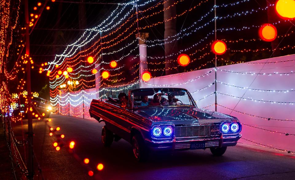 A 1964 Chevrolet Impala lowrider bounces up and down through the tunnel of lights while driving with the rest of a car club organized to take kids through the Magic of Lights show at the Empire Polo Club in Indio, CA.