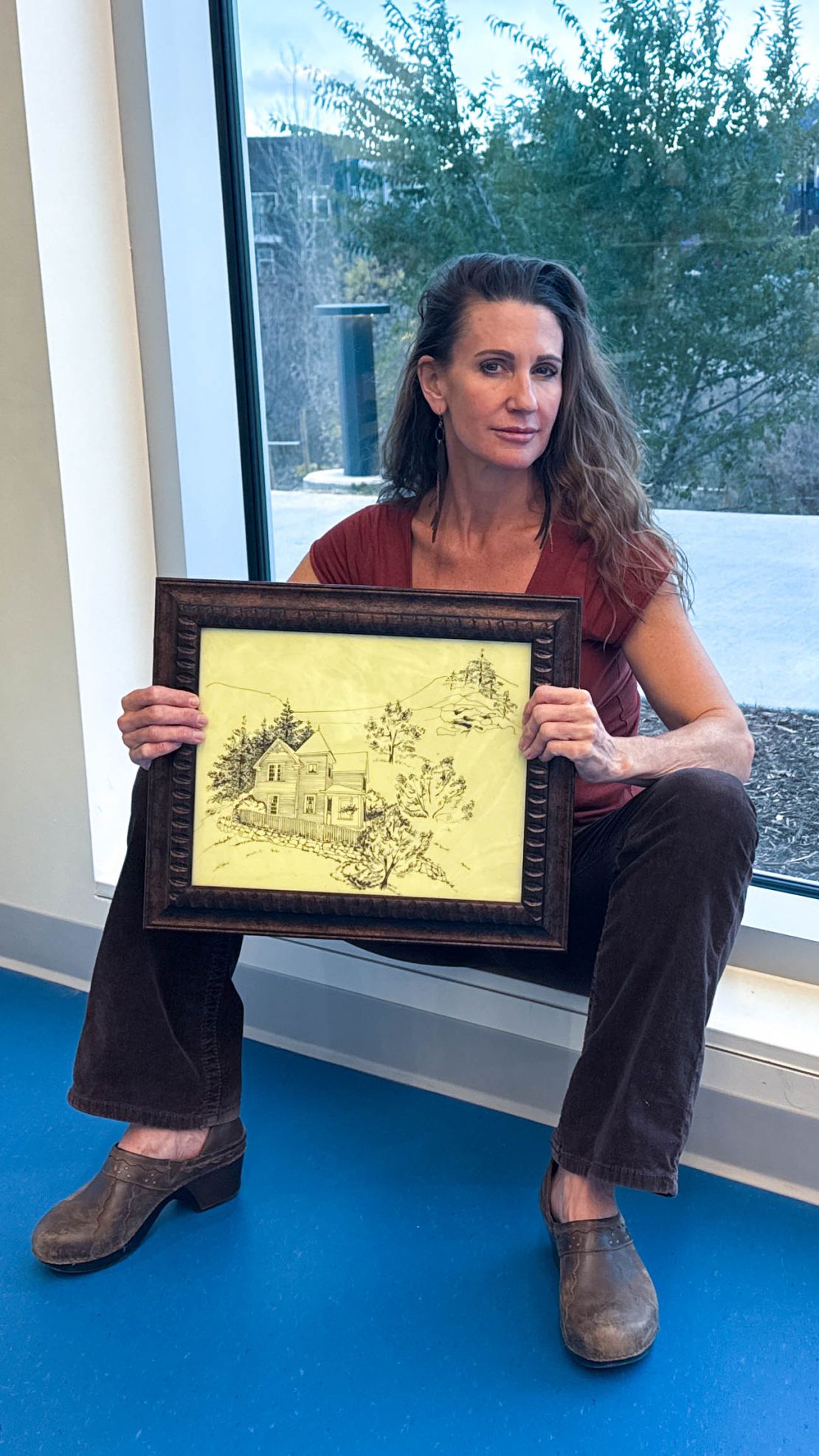 Sarah Jane Romano poses on November 19, 2024, with a drawing of her former home, which was destroyed in the 2013 flood event in Boulder County, Colorado.