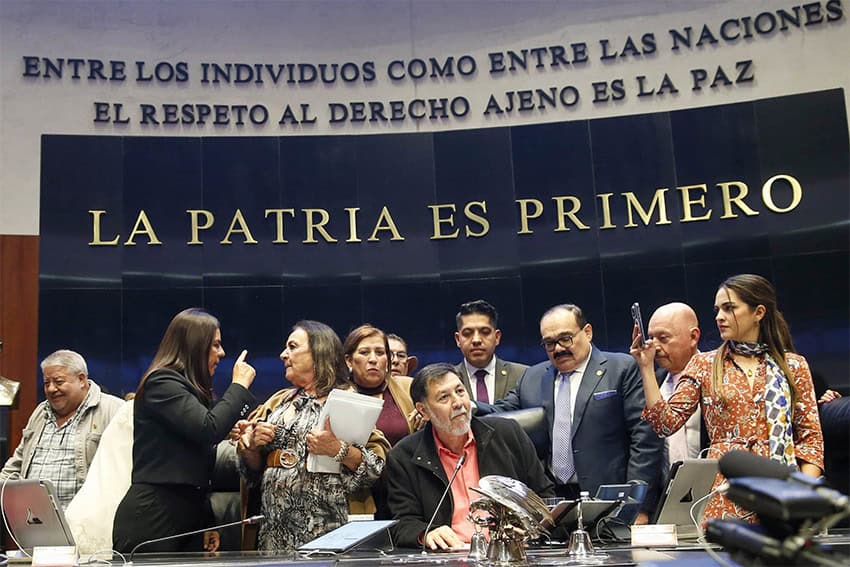 Senate President Gerardo Fernández Noroña, of the Morena party, sits on a legislative dias in front of the words