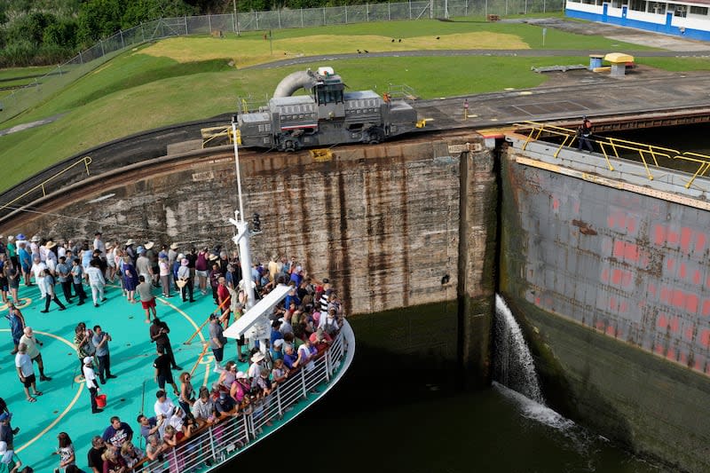 Passengers stand on the forward of the Brilliance of the Seas cruise ship as the vessel approaches the gates of Miraflores Locks to become the first cruiser of the season to pass through the Panama Canal in Panama City, Monday, Oct. 7, 2024. | Matias Delacroix