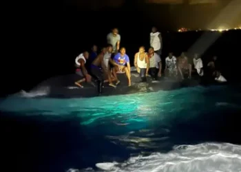Royal Bahamas Defence Force via Reuters Survivors of a migrant boat that capsized perch on the overturned vessel off the coast of New Providence