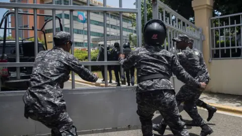 Getty Images Police scramble to enter the ministerial premises after a friend of Orlando Jorge Mera shot and killed him in his office