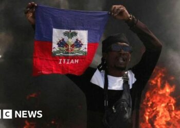 A man drives past a burning barricade during a protest against Prime Minister Ariel Henry's government and insecurity, in Port-au-Prince, Haiti March 1, 2024