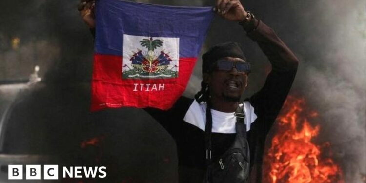 A man drives past a burning barricade during a protest against Prime Minister Ariel Henry's government and insecurity, in Port-au-Prince, Haiti March 1, 2024