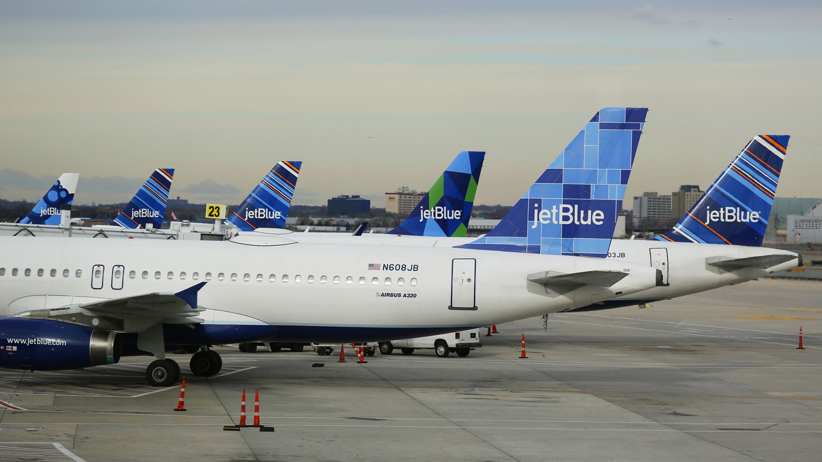 Several JetBlue Airbus A320 aircraft parked on the apron at New York JFK Airport.