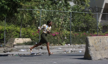 A woman runs for cover from gunfire during clashes between police and gangs in the Delmas neighborhood of Port-au-Prince, Haiti, Monday, Dec.