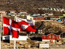 Greenlandic and Danish, left, flags flutter in Ilulissat, western Greenland. June 2022.