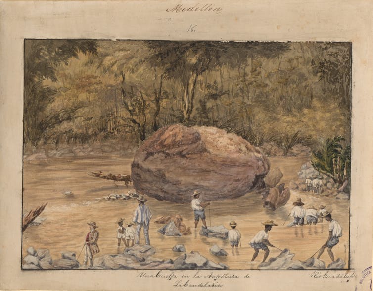 A dozen men in uniforms work in a river with ropes and sticks, European men overseeing, a large rock in the middle of the river.