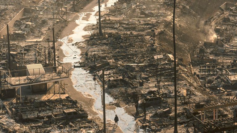 A person walks amid the destruction left behind by the Palisades Fire in the Pacific Palisades neighbourhood of Los Angeles, Thursday, Jan. 9, 2025. (AP Photo/Jae C. Hong)