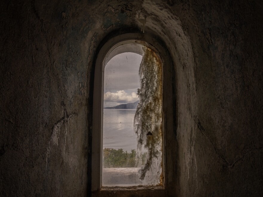 A window view from inside the San Isidro Lighthouse, which is located at the southern tip of the Brunswick Peninsula, in the region of Magallanes and Chilean Antarctica in Chile, with the Darwin Mountain Range in the background.