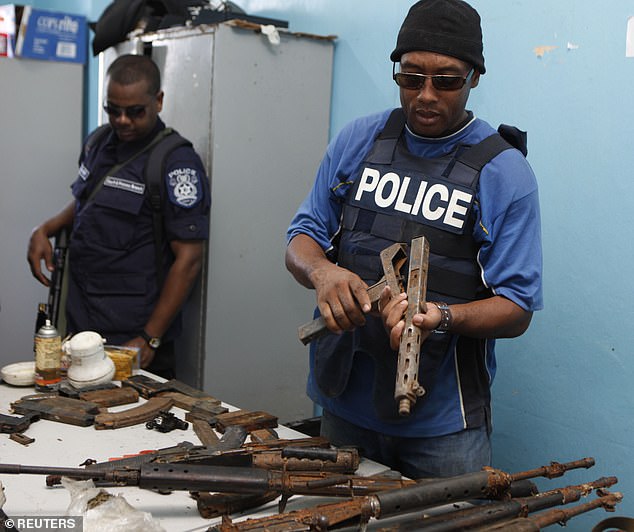 Police officers inspect rifles and ammunition found buried during a 2011 raid in Rincon Forest in Las Cuevas. Gun violence in the dual-island state has since climbed to an all-time high