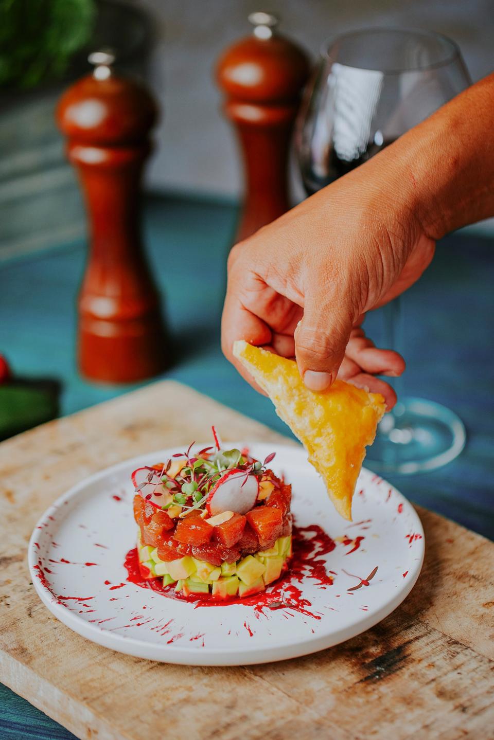 A tuna tartare tower on a sauce splattered plate.