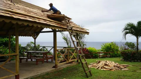 Gemma Handy A man fixes the roof in Salybia