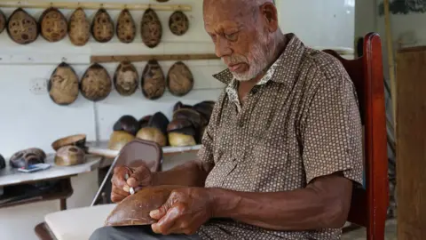 Gemma Handy Faustulus Frederick decorating a calabash gourd