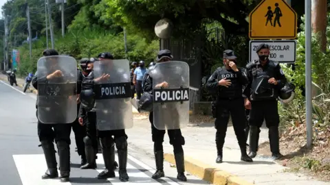 Reuters Nicaraguan police officers stand in formation as they block journalists working outside the house of opposition leader Cristiana Chamorro