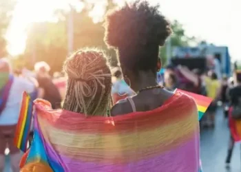 Getty Images Young female couple hugging with rainbow scarf at pride event