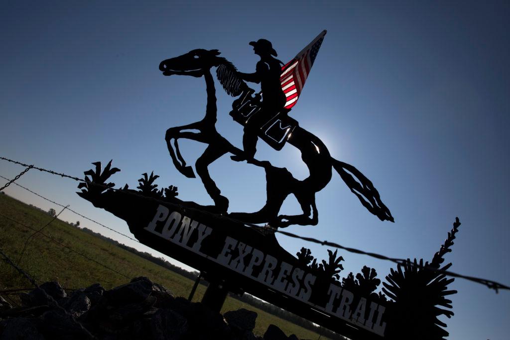 A sculputre of a man on horseback, holding and American Flag with a sign underneath reading 'Pony Express Trail'