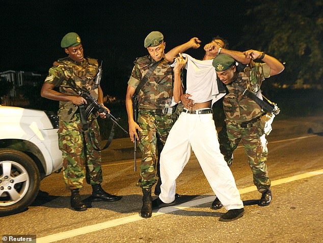 Soldiers patrolling the streets in Cunupia, central Trinidad, assist a drunken man. A state of emergency has been declared in the country after a record 624 murders last year