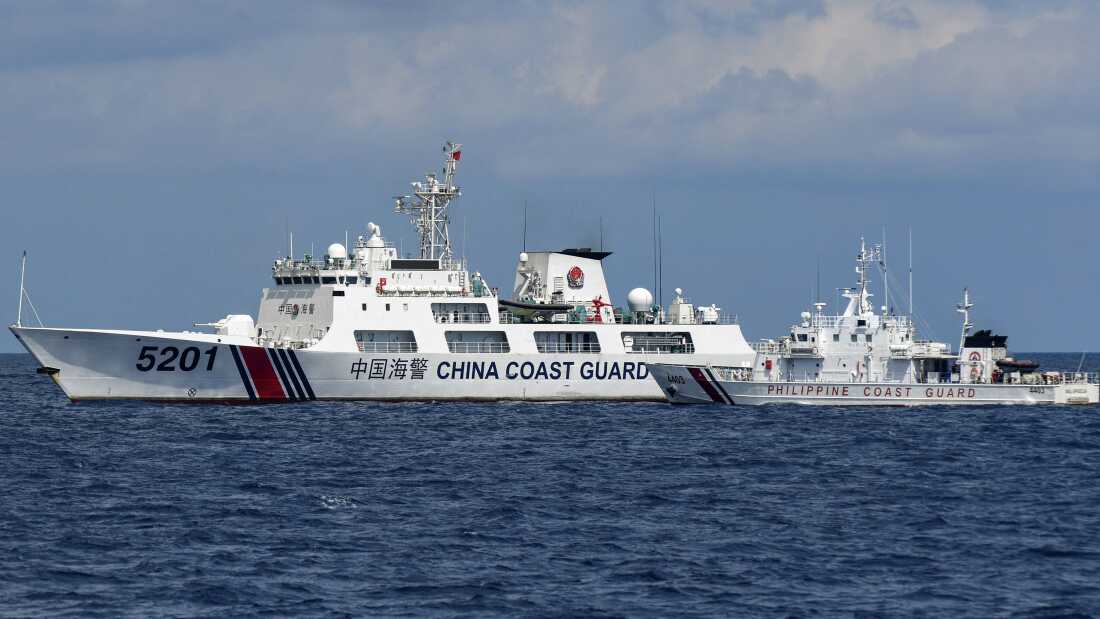 A Philippine coast guard vessel maneuvers as a Chinese coast guard ship cuts its path in the disputed South China Sea