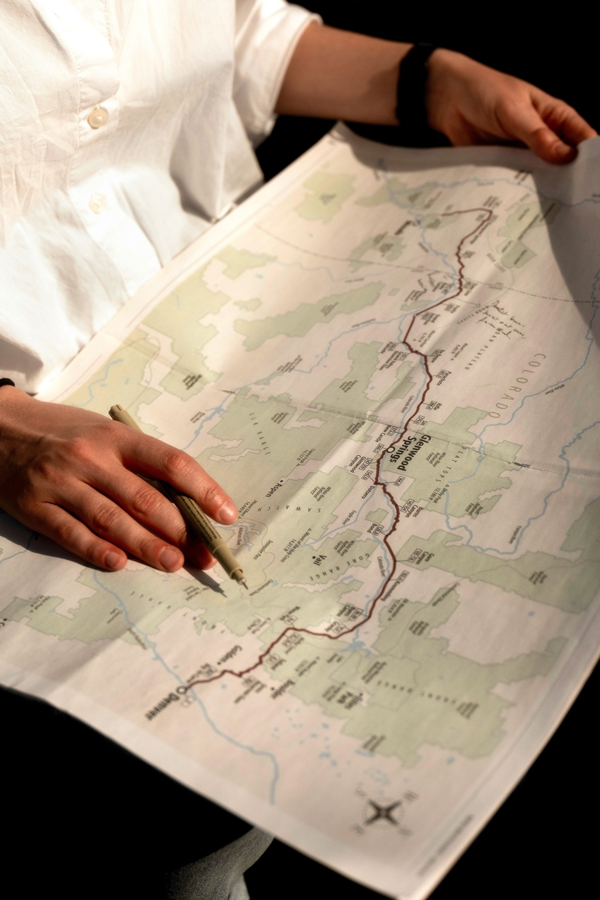 A person is tracing the train's route on a map of the Rocky Mountains on their lap.