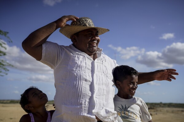 Luis Barliza, 48, a member of the Indigenous Wayuu community, prepares to pose for a photo with his children on the outskirts of Cabo de la Vela, Colombia, Friday, Feb. 7, 2025. (AP Photo/Ivan Valencia)