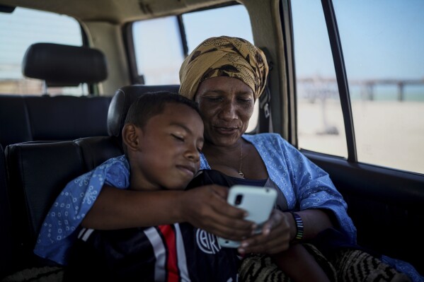 Teacher and Indigenous member of the Wayuu community Kelmis Maria Gonzalez, 45, and her son David, watch videos on her cell phone in Mayapo, Colombia, Thursday, Feb. 6, 2025. (AP Photo/Ivan Valencia)