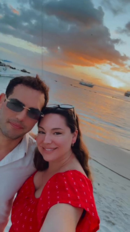 Couple posing on a beach at sunset.