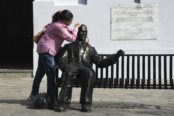 A woman embraces a statue of José Gregorio Hernandez, the physician known as the 